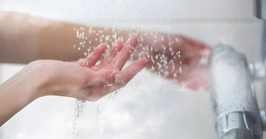Hand checking the shower's water temperature