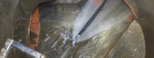 A high-pressure water jet is being used to clean the inside of a sewer pipe.
