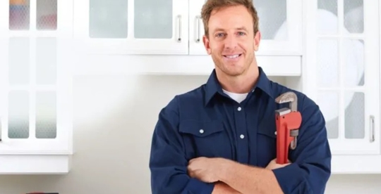 A plumber is smiling while holding a wrench