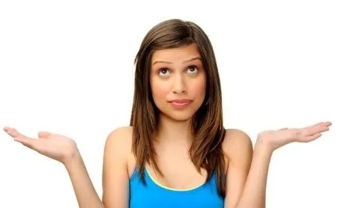 A woman with brown hair stands in confusion with open palms.