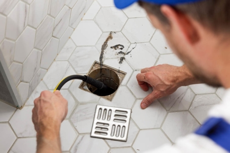 A plumber inspecting a bathroom drain