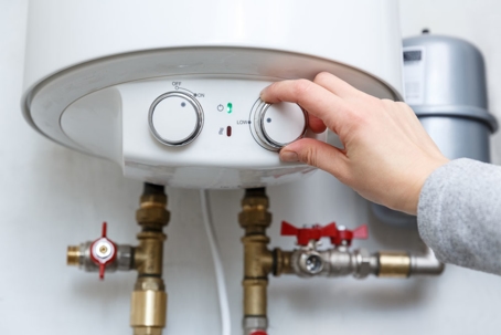 person changes settings on a water heater