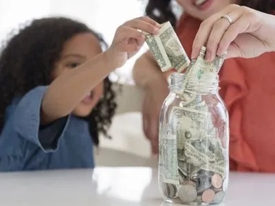 A mother and a daughter putting money into a jar