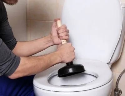 A person is unclogging a toilet