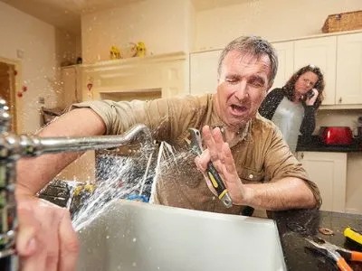 A  man is struggling to fix a sink