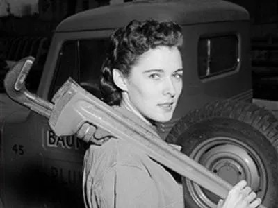 A woman is carrying a wrench on her shoulder