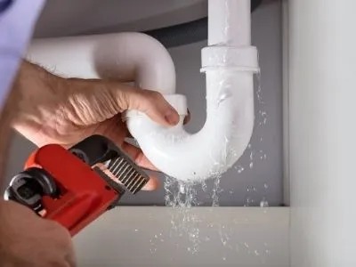 A plumber fixing a leaking pipe