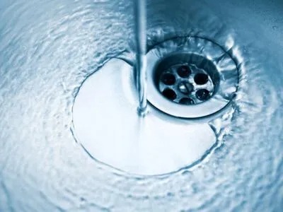 Water swirls down a drain.