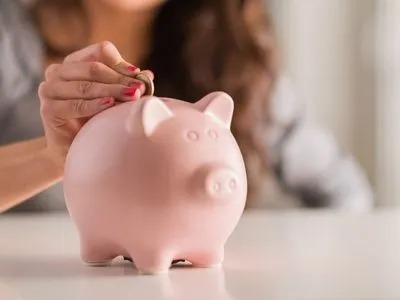 A woman putting a coil into a piggy bank