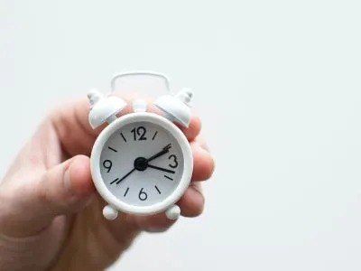 A person is holding a tiny clock