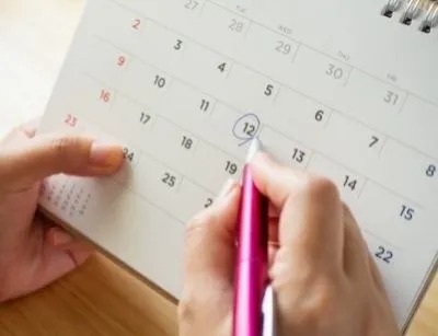 A person is marking a date on a calendar