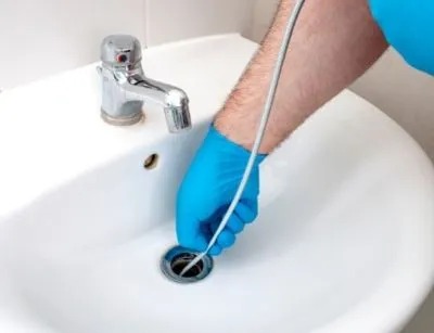 A plumber is trying to unclog a sink