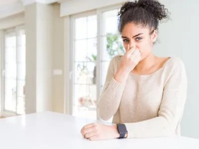 A woman pinches her nose, seemingly disgusted by a bad smell.