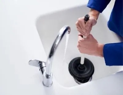 A person is trying to unclog a sink drain