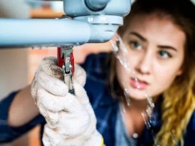 A woman fixing a leaking pipe