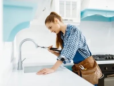 A woman is fixing a faucet