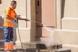 A worker uses a power washer.