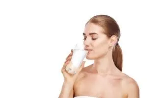 A fair-skinned person drinks a glass of water.